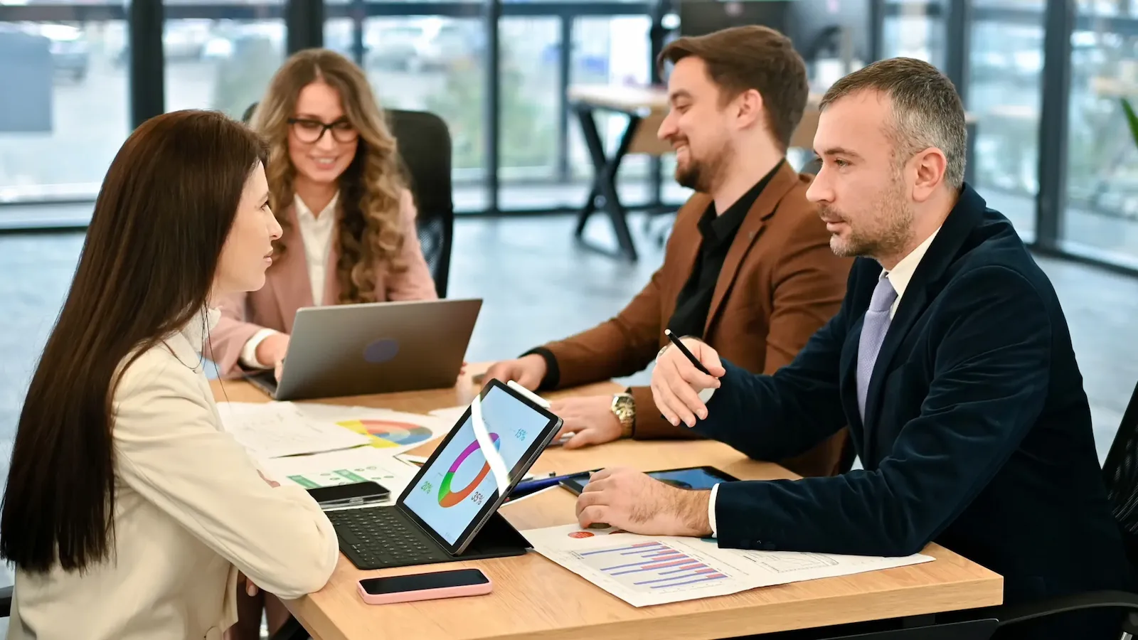 business professionals collaborate at a table with laptops, discussing contingent workforce strategies and direct sourcing.
