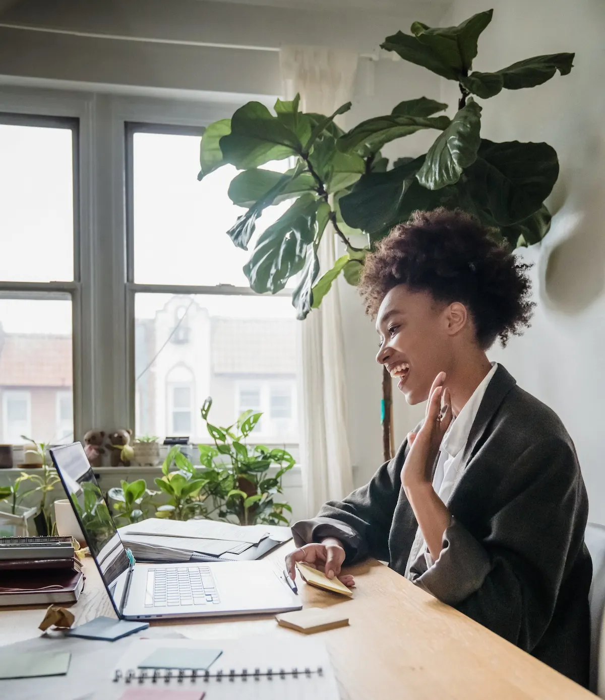 A woman sitting at a desk with a laptop, participating in an online meeting as an employee.